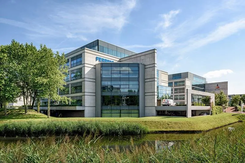 Modern kantoorgebouw aan de Polarisavenue met glazen gevels, omringd door groen en een vijver.