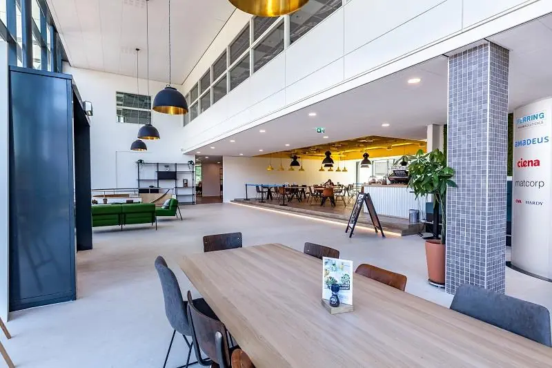 Moderne, open kantoorruimte aan de Polarisavenue met zithoeken, vergadertafels en een koffiebar.