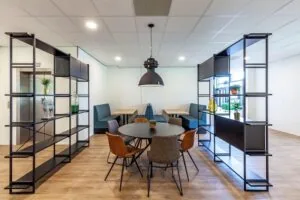 Moderne kantoorruimte aan de Polarisavenue met ronde vergadertafel, zitbanken en open stalen kasten.