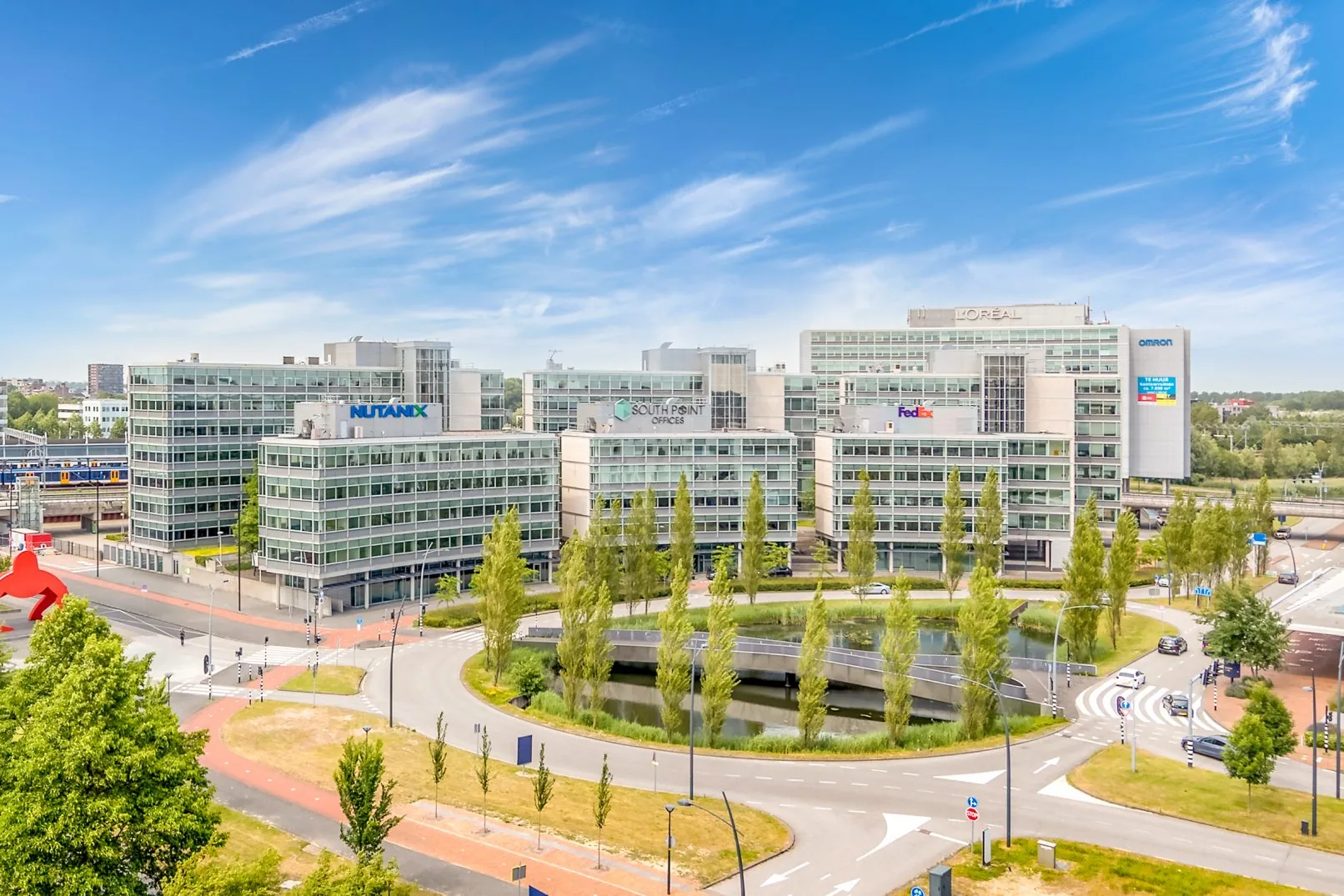 Kantoorgebouwen van het South Point Offices-complex in Amsterdam, met zicht op bedrijfslogo’s zoals Nutanix, FedEx en L’Oréal.