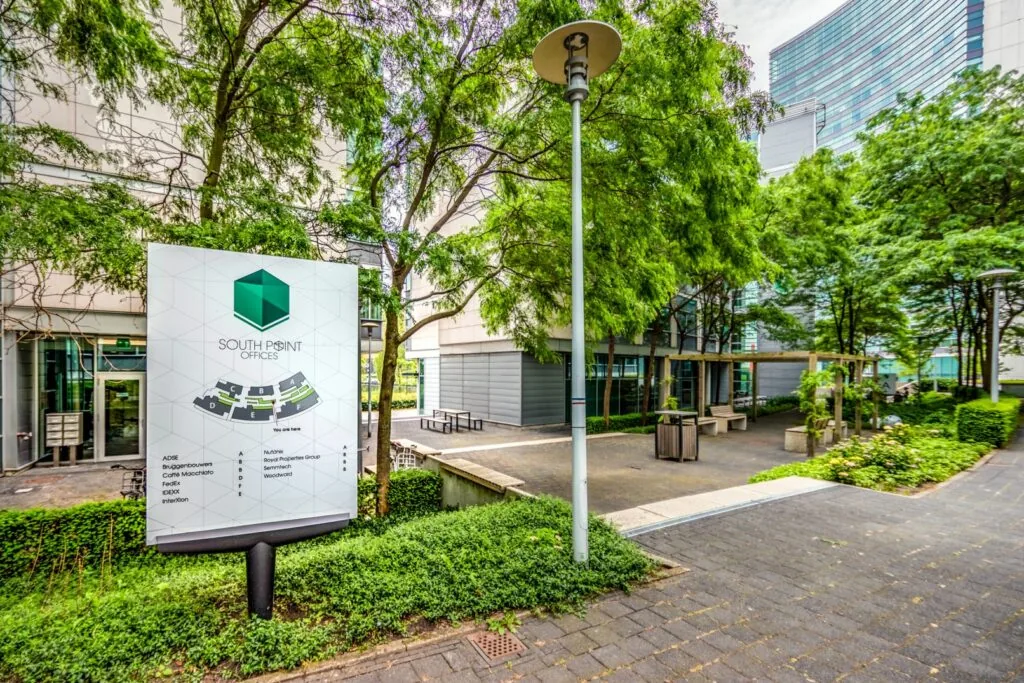 Informatiebord van South Point Offices in een groene, modern aangeklede kantoortuin.