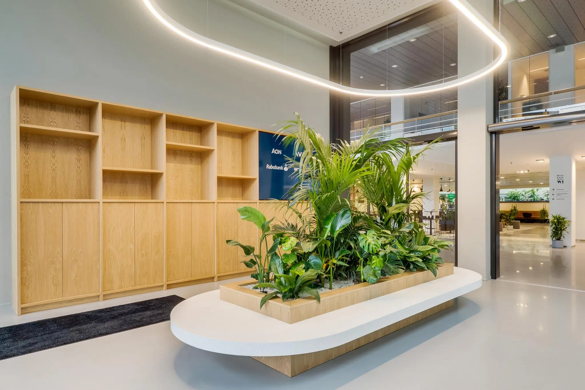 Moderne entreehal aan de Winthontlaan met een grote plantenbak, houten kastenwand en strakke verlichting.