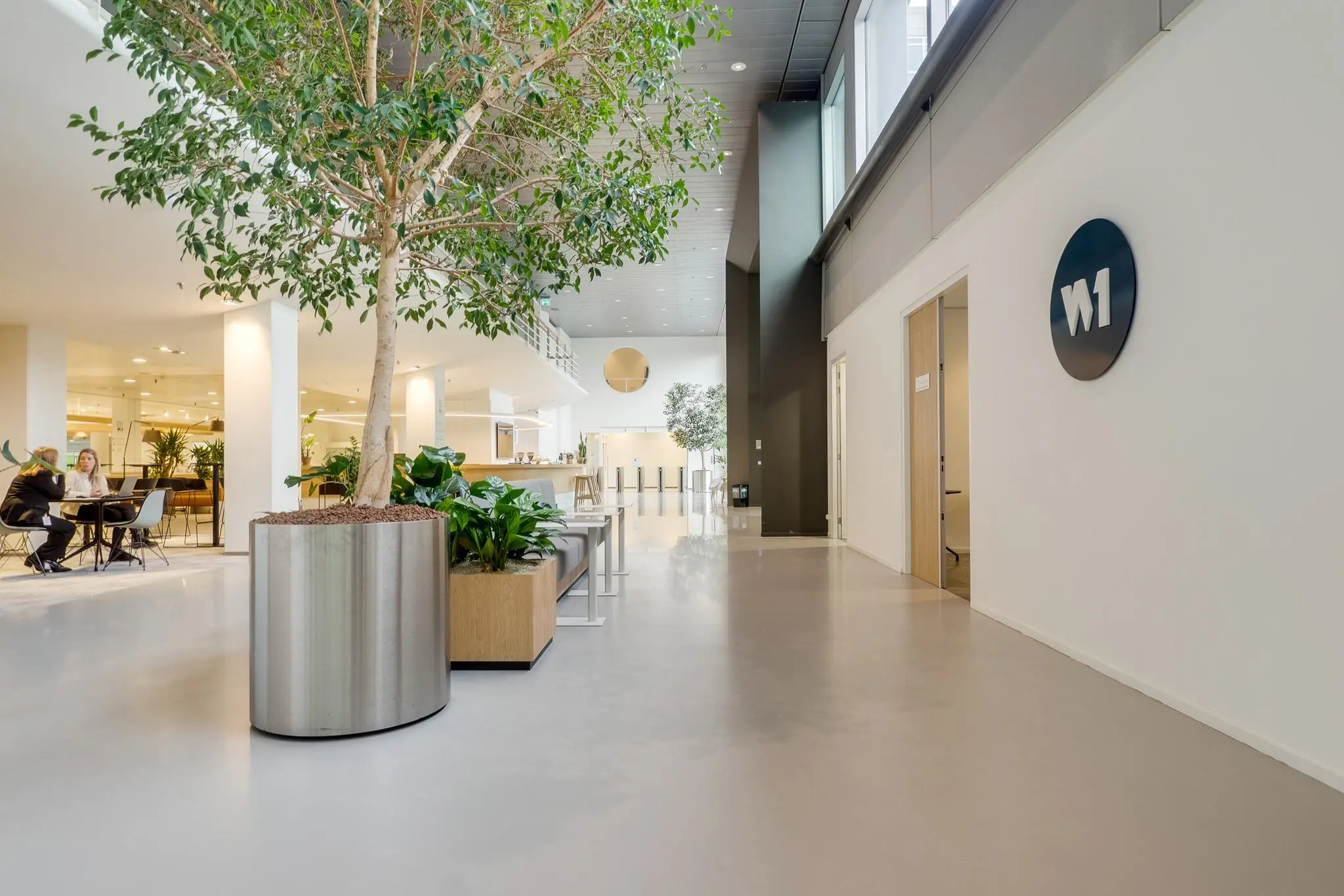 Moderne en lichte kantoorlobby aan de Winthontlaan met zitgelegenheid, grote plantenbakken en het W1-logo aan de muur.