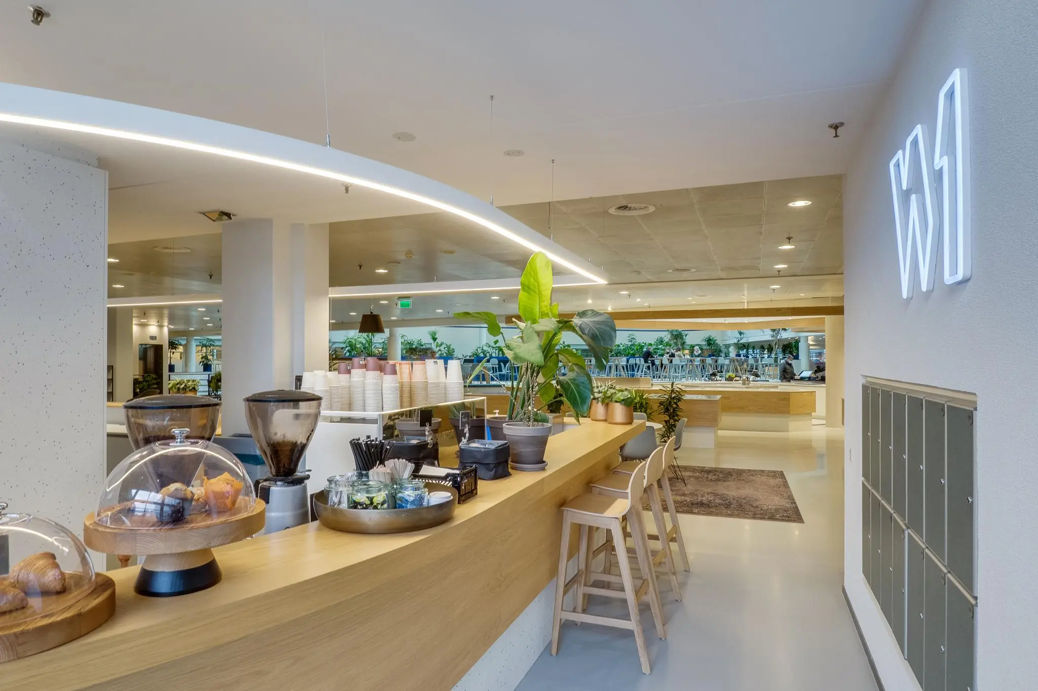Modern ingerichte koffiebar met houten toonbank en zitplekken in een bedrijfsverzamelgebouw aan de Winthontlaan.