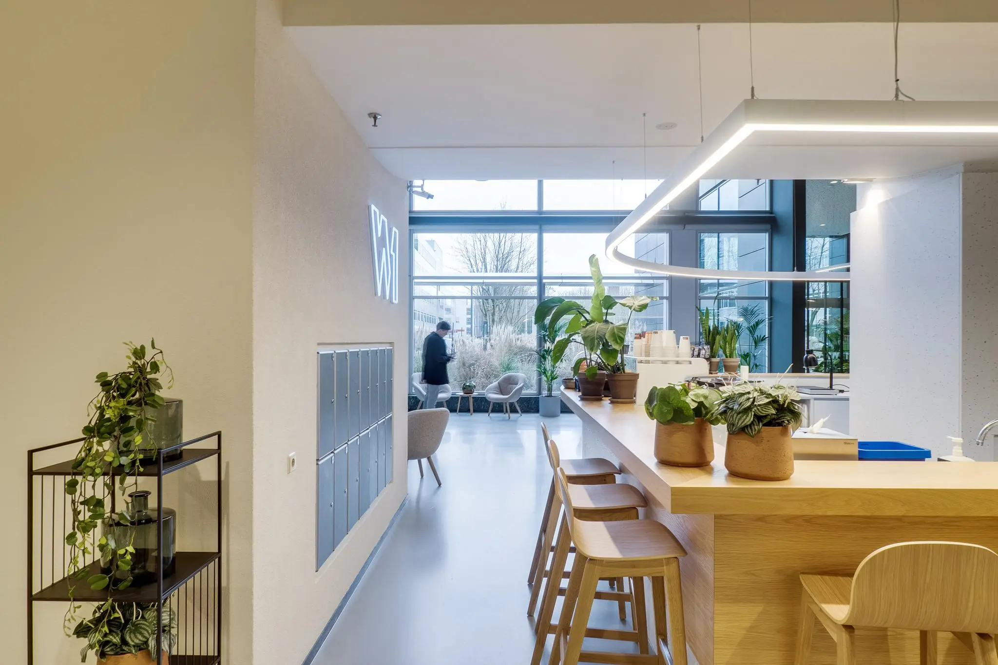 Moderne, lichte kantoorruimte aan de Winthontlaan met houten bar, planten en zithoek bij raam.