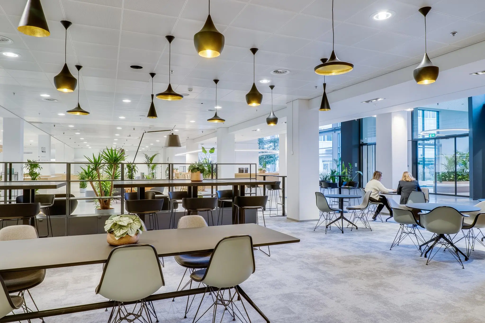 Modern ingerichte kantoorruimte aan de Winthontlaan met zitjes, hanglampen en veel groen.