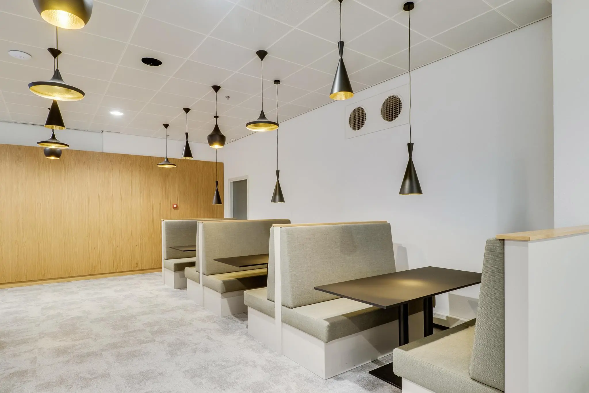 Moderne zitruimte aan de Winthontlaan met hoge banken, zwarte tafels en hanglampen in een strak interieur.