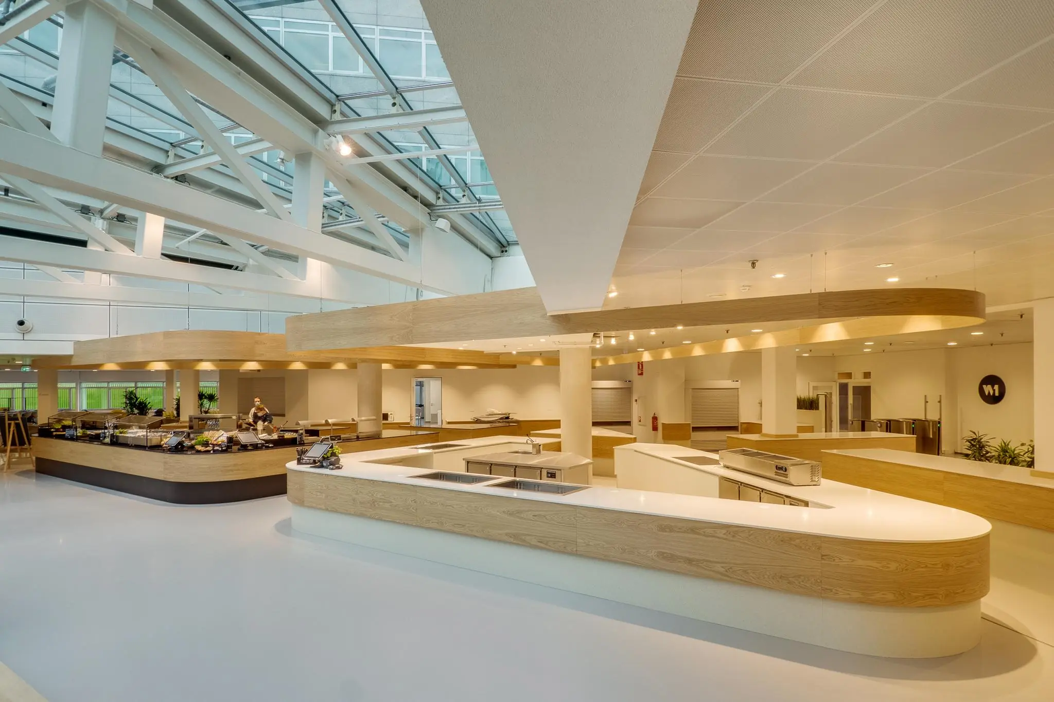 Moderne, open bedrijfskantine aan de Winthontlaan met houten en witte afwerkingen en een glazen dak.