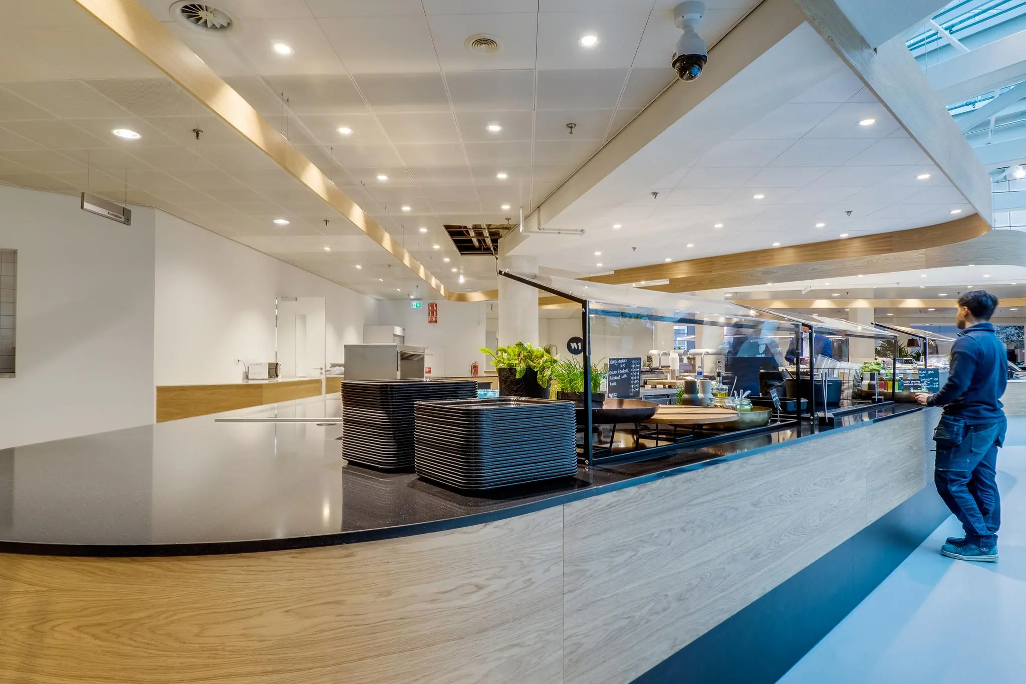 Modern bedrijfsrestaurant aan de Winthontlaan met uitgiftebalie, stapel dienbladen en een persoon die bediend wordt.