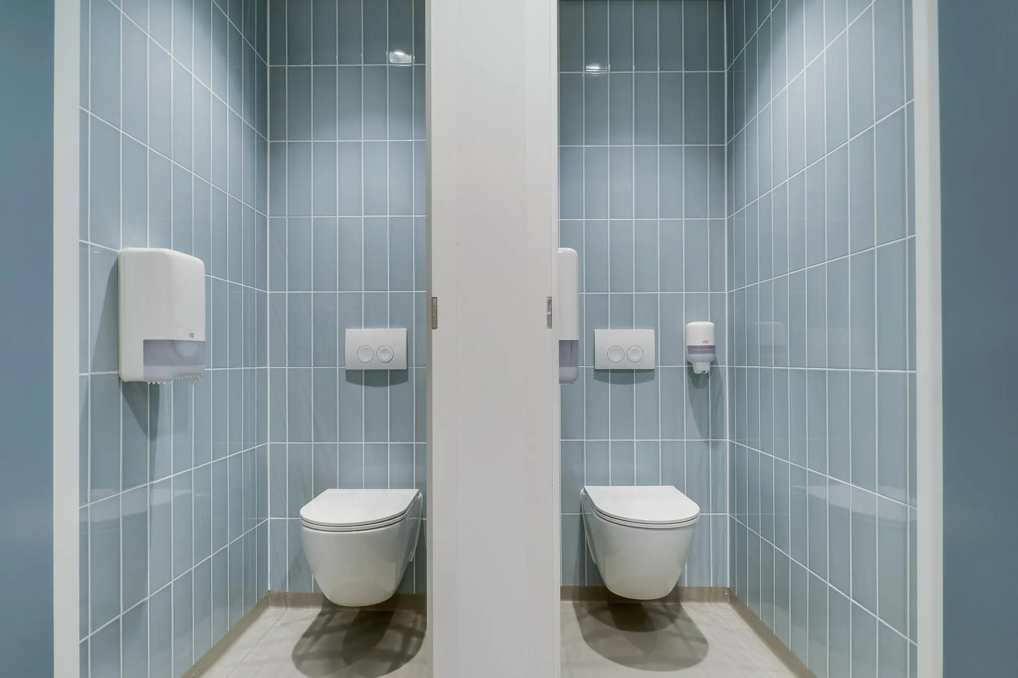 Twee moderne toiletruimtes met blauwe tegels en wandhangende toiletten aan de Winthontlaan.