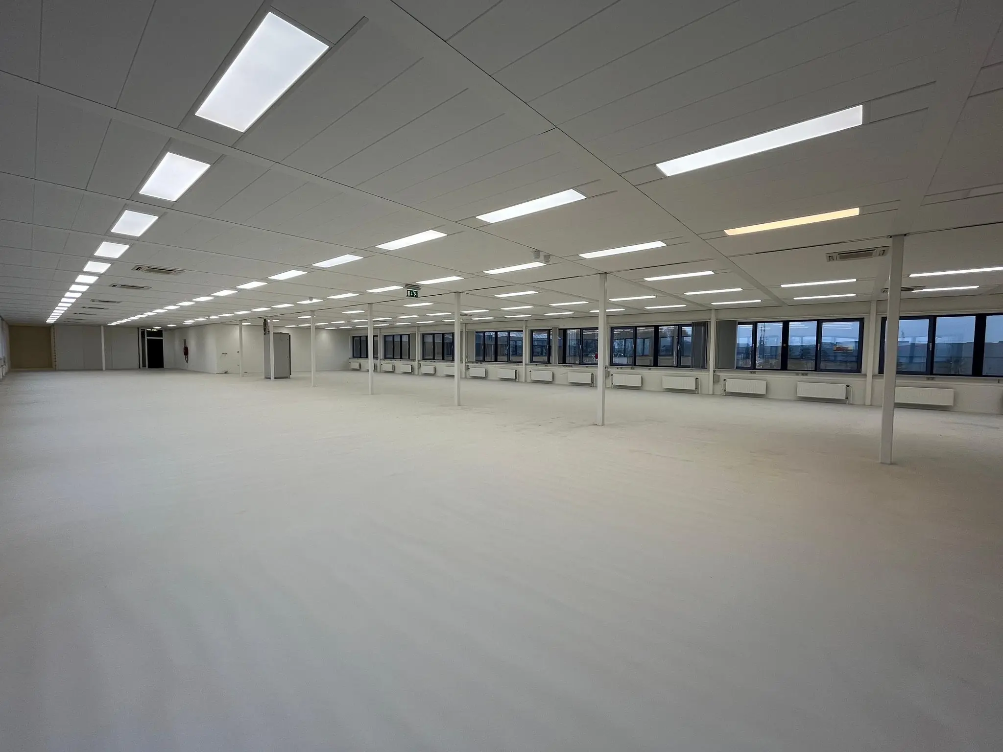 Leeg en ruim kantoorpand aan de Kernkade met witte vloer, systeemplafond en grote ramen.