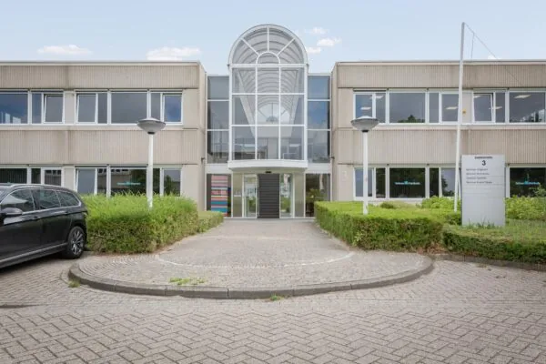 Vooraanzicht van een kantoorgebouw aan de Energieweg 3 met een moderne glazen entree en bedrijfsnaambord op het trottoir.