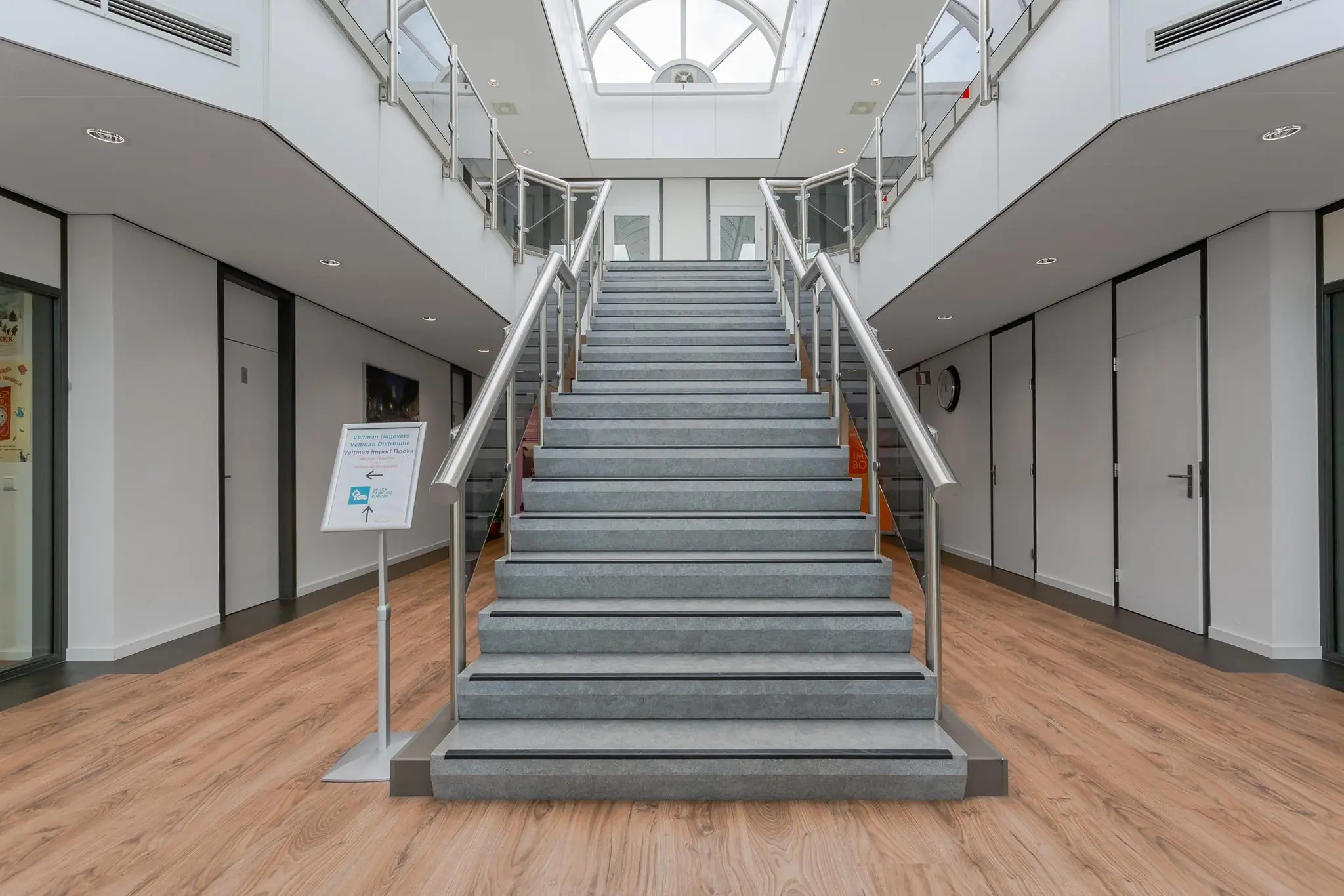 Brede grijze trap met metalen leuningen in een modern kantoorgebouw aan de Energieweg.
