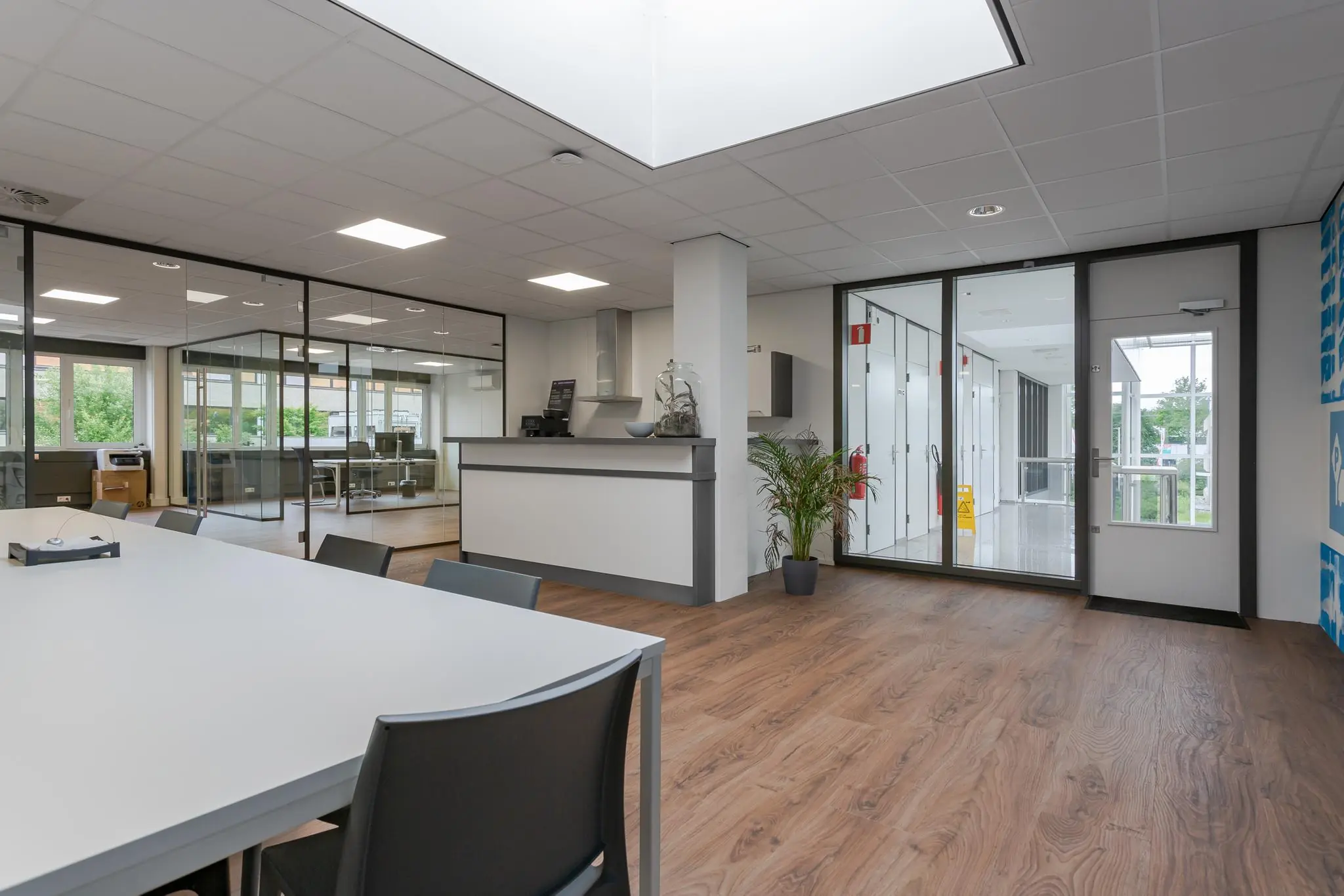 Moderne kantoorruimte aan de Energieweg met glazen vergaderruimtes, ontvangstbalie en houtlook vloer.