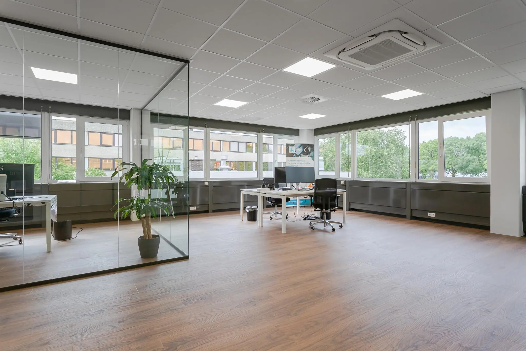 Modern en licht kantoor aan de Energieweg met grote ramen, glazen wanden en houten vloer.