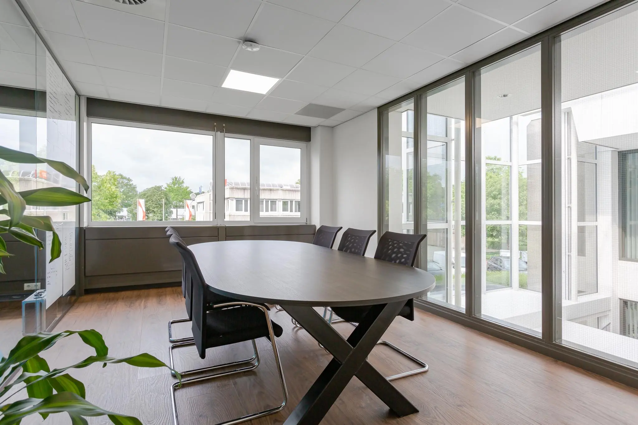 Vergaderruimte met ovale tafel, zes stoelen en grote ramen in een modern kantoorpand aan de Energieweg.