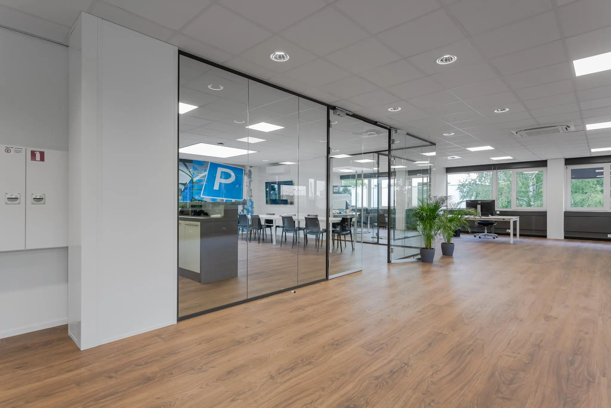 Modern kantoorinterieur aan de Energieweg met glazen vergaderruimte, houten vloer en grote ramen.