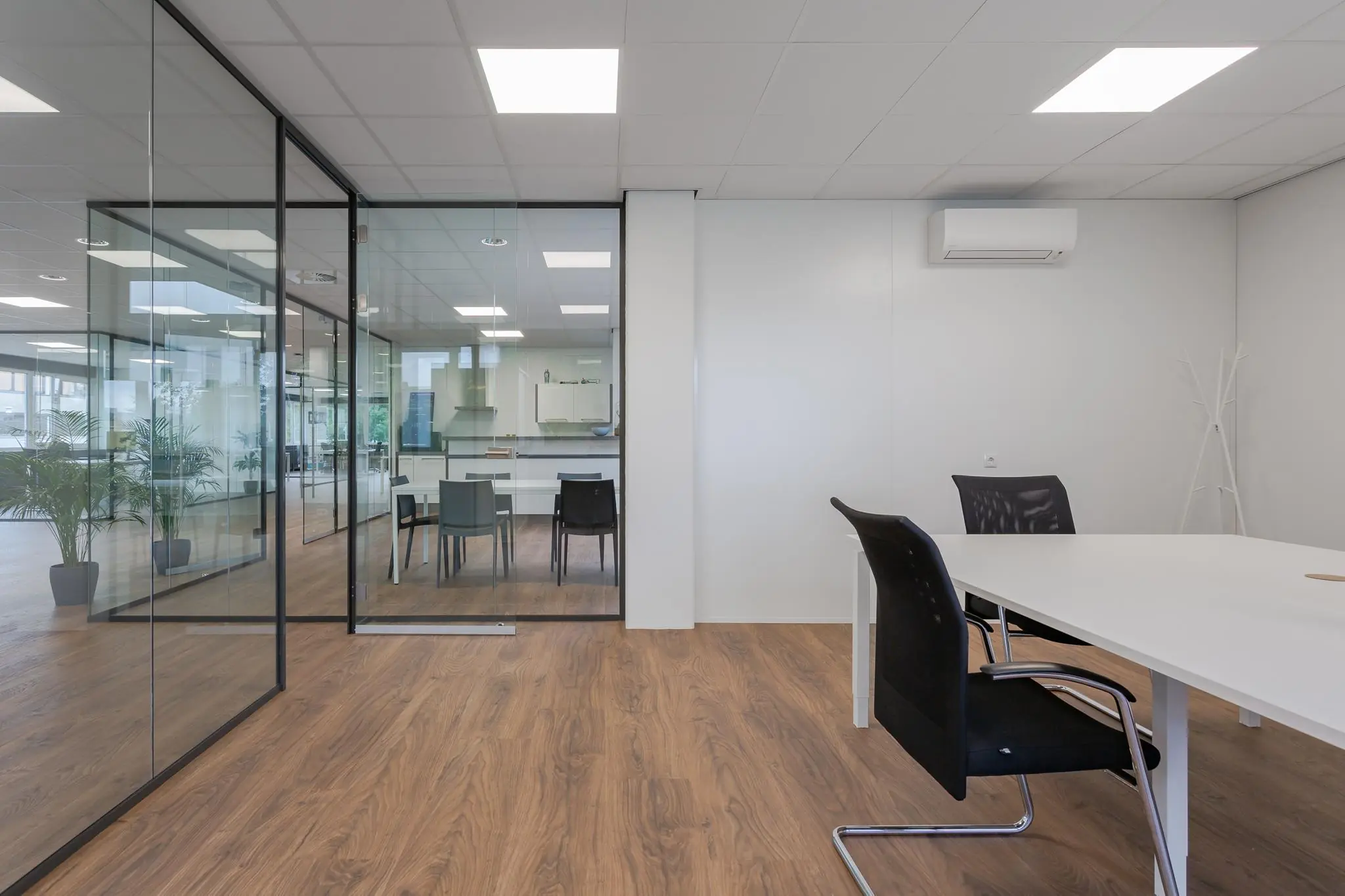 Moderne, lichte vergaderruimte met glazen wanden, zwarte stoelen en een houten vloer aan de Energieweg.