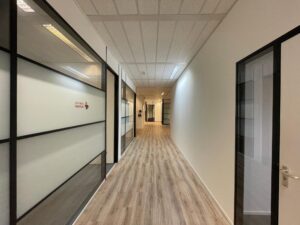 Lichte, moderne kantoorhal met glazen wanden en het logo van Vereniging Eigen Huis.