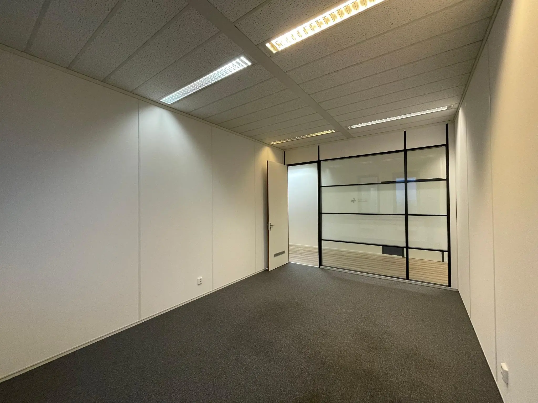 Lege kantoorruimte aan de Zekeringstraat met glazen tussenwand en systeemplafond.