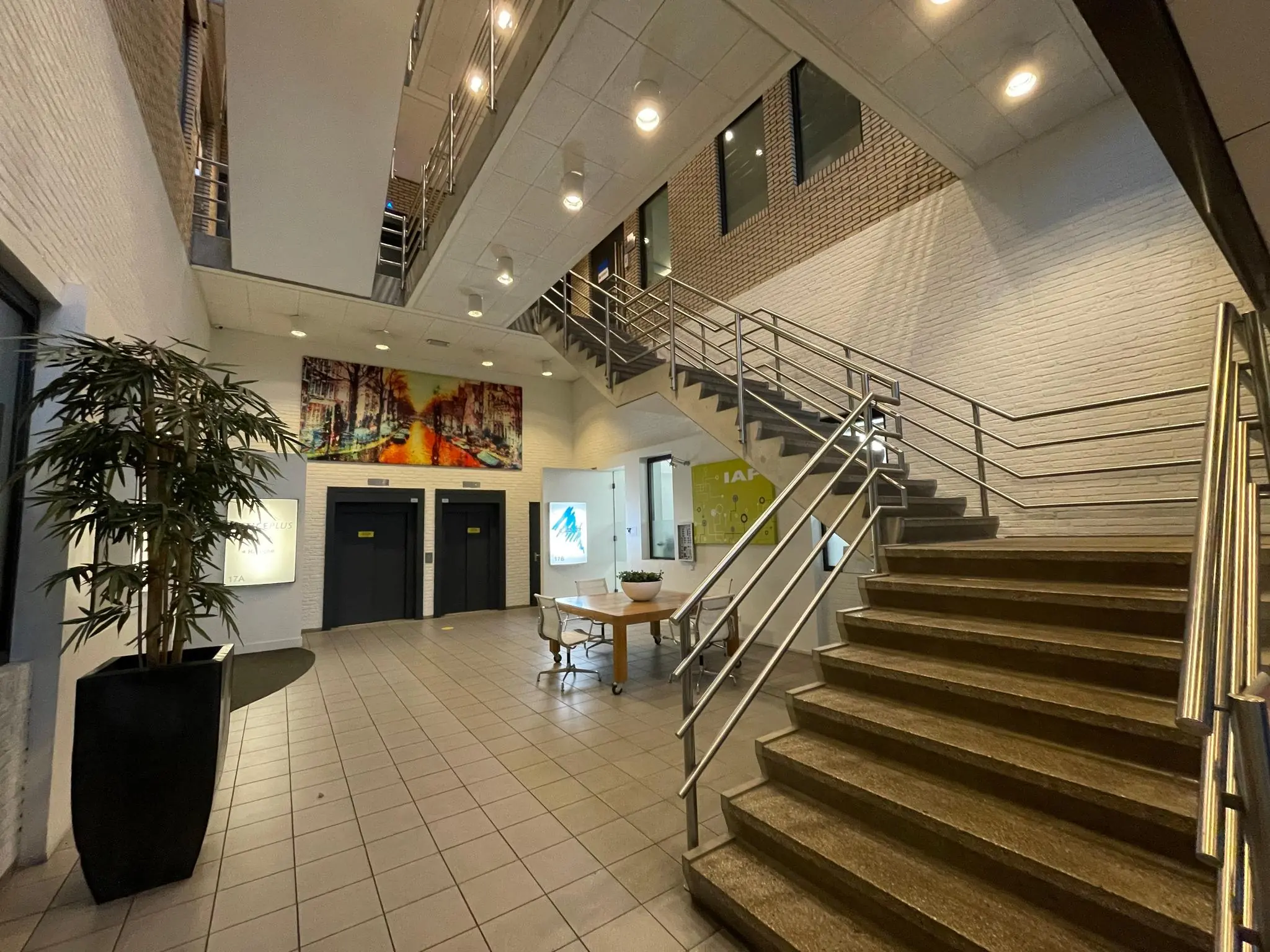 Moderne entreehal aan de Zekeringstraat met liften, trap, kunstwerk aan de muur en een zithoek.