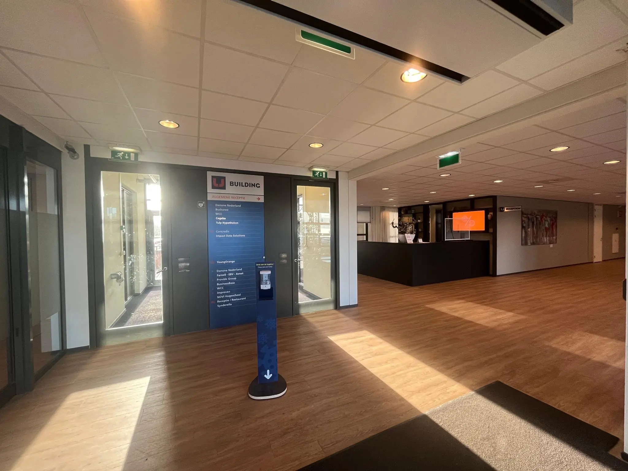 Ingang en receptie van het bedrijfsverzamelgebouw Zonnebaan, met bewegwijzering en balie zichtbaar.
