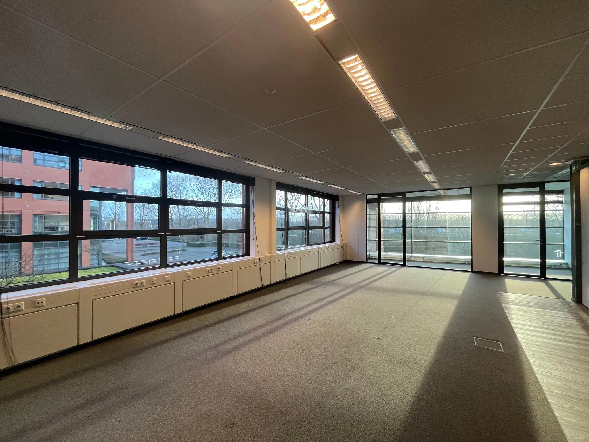 Lichte, lege kantoorruimte aan de Zonnebaan met grote ramen en uitzicht op buiten.