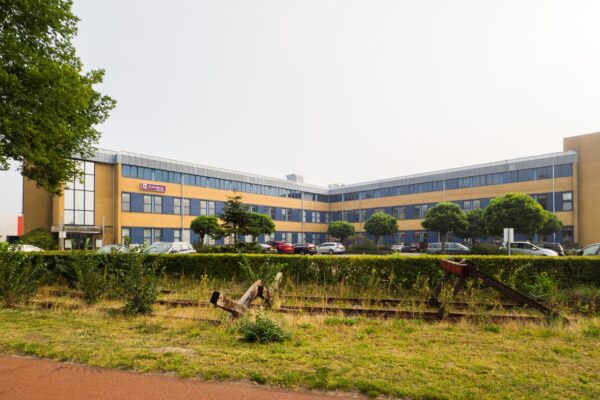Kantoorgebouw aan de Kernkade met het logo van het bedrijf Externet op de gevel en een beëindigd stuk spoor op de voorgrond.