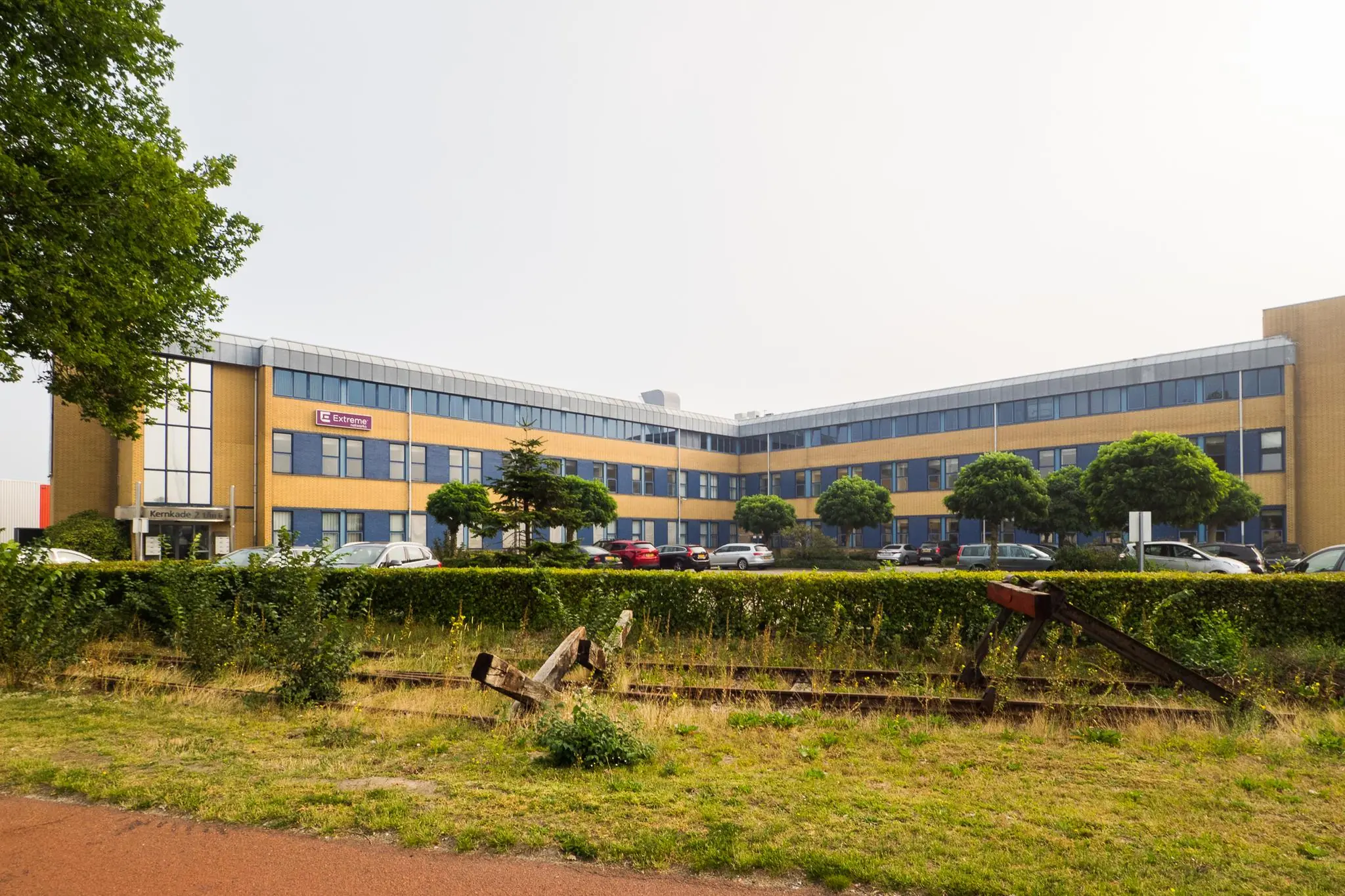Kantoorgebouw aan de Kernkade met het logo van het bedrijf Externet op de gevel en een beëindigd stuk spoor op de voorgrond.