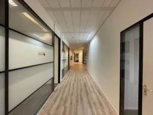 Gang in een modern kantoorgebouw aan de Zekeringstraat met glazen kantoren van Vereniging Eigen Huis.