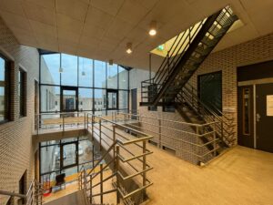 Trapportaal met metalen trap en grote ramen in een modern gebouw aan de Zekeringstraat.