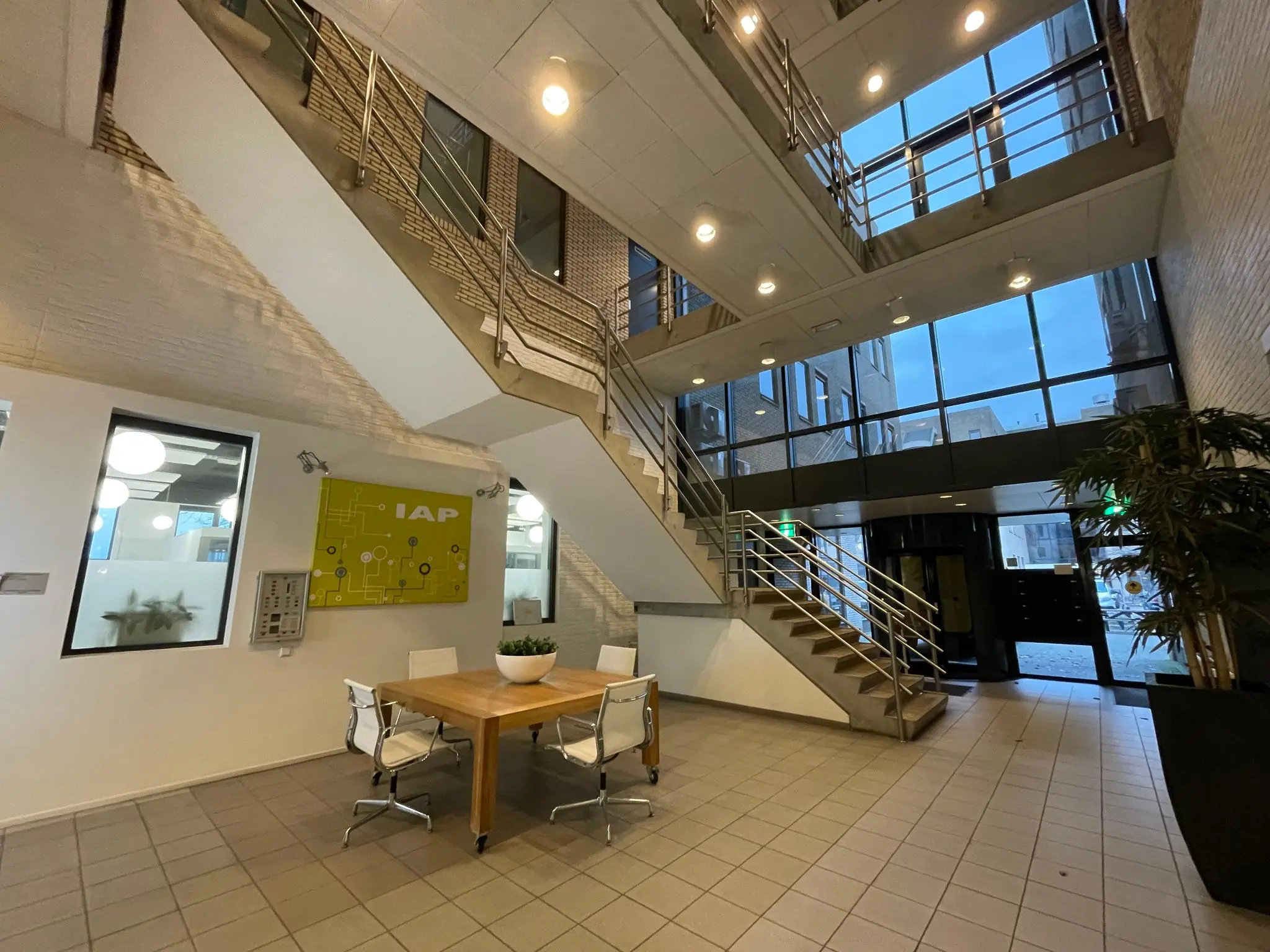 Moderne entreehal van een kantoorgebouw aan de Zekeringstraat met glazen gevel, trap en vergadertafel.