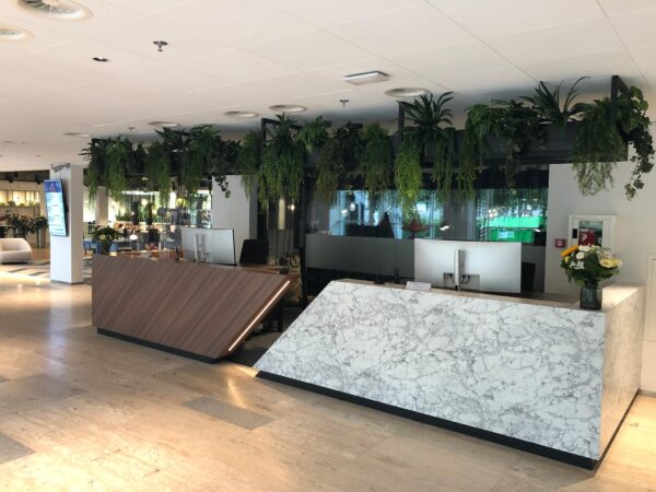 Moderne receptiebalie in een open kantoorruimte aan de Newtonlaan, met hangende planten en marmeren afwerking.
