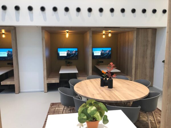 Moderne kantoorruimte aan de Newtonlaan met houten zitnissen, ronde vergadertafel en decoratieve planten.