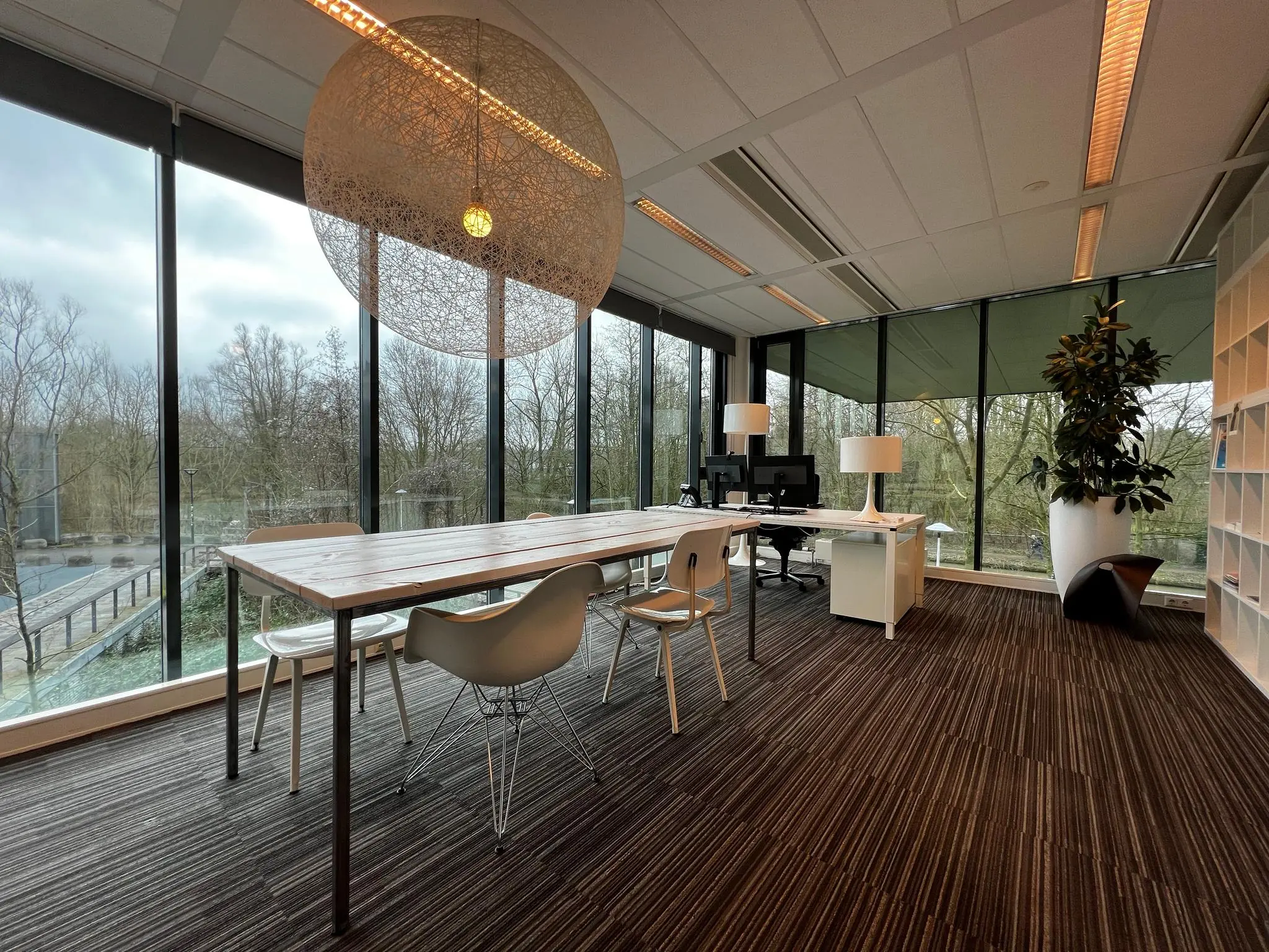 Modern kantoorinterieur op het Herculesplein met grote ramen, strakke meubels en uitzicht op een groene omgeving.