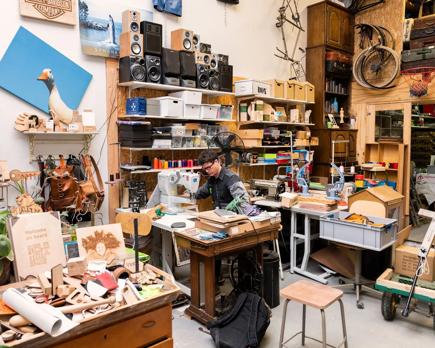 Creatieve werkruimte in Steiger 24 in Almere met een man die werkt aan een naaimachine te midden van diverse gereedschappen en materialen.