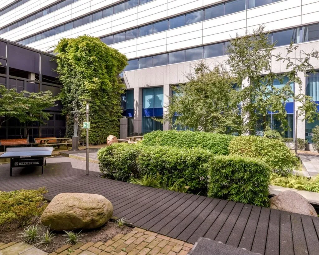 Binnentuin van het Coengebouw aan de Kabelweg 37 in Amsterdam met groenvoorziening, zitbanken en tafeltennistafel.