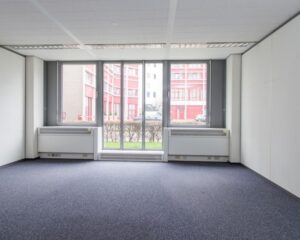 Lichte, lege kantoorruimte met tapijtvloer aan de Gaetano Martinolaan 75-95 in Maastricht.