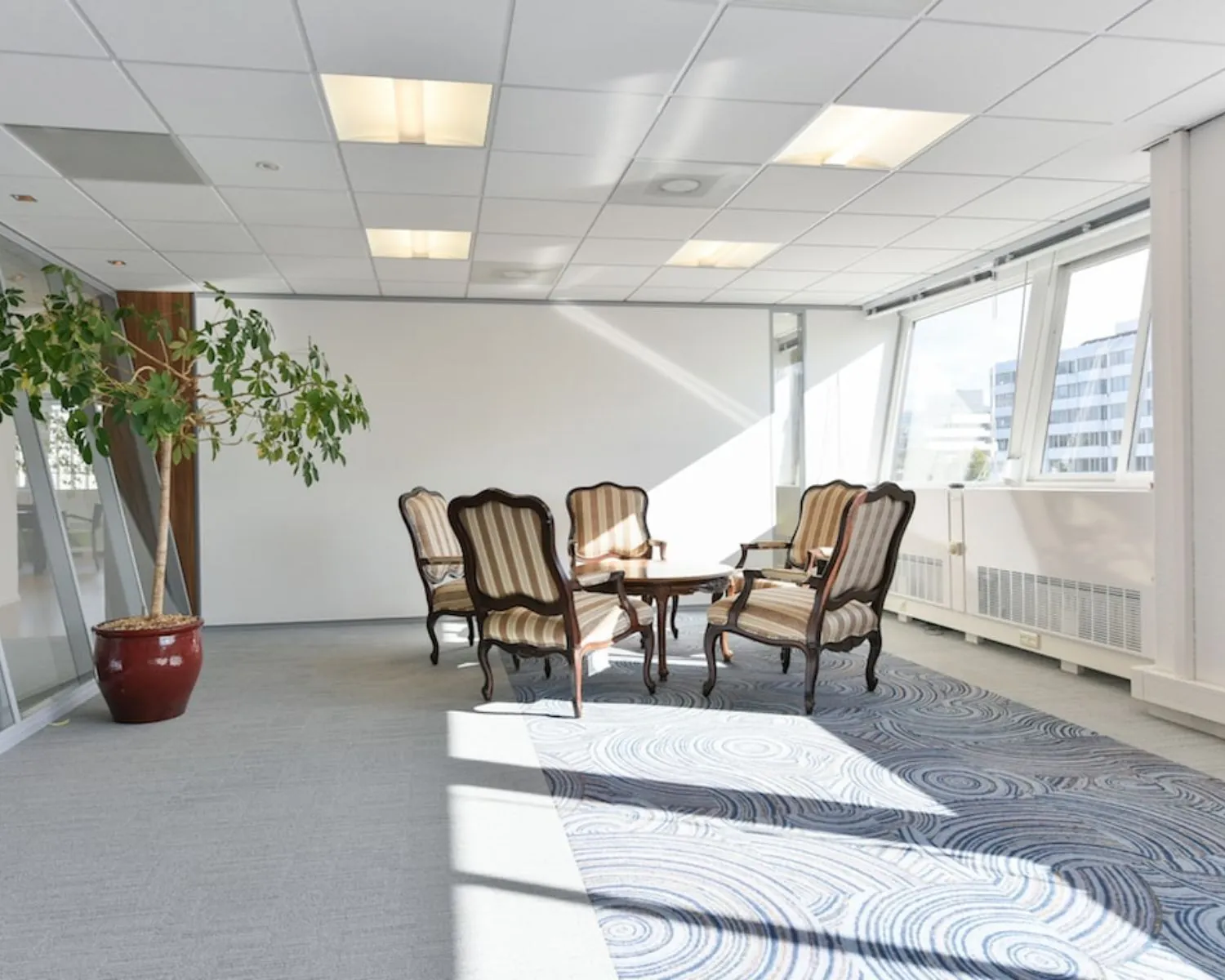 Zonnige kantoorruimte aan de Treubstraat 1 in Rijswijk met klassieke zitmeubels en grote ramen.