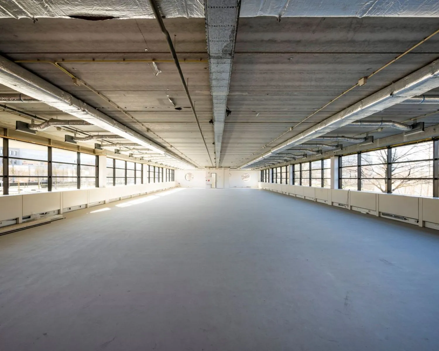 Ruime, lege kantoorruimte met industriële afwerking en grote raampartijen aan de Wegalaan 35 in Hoofddorp.