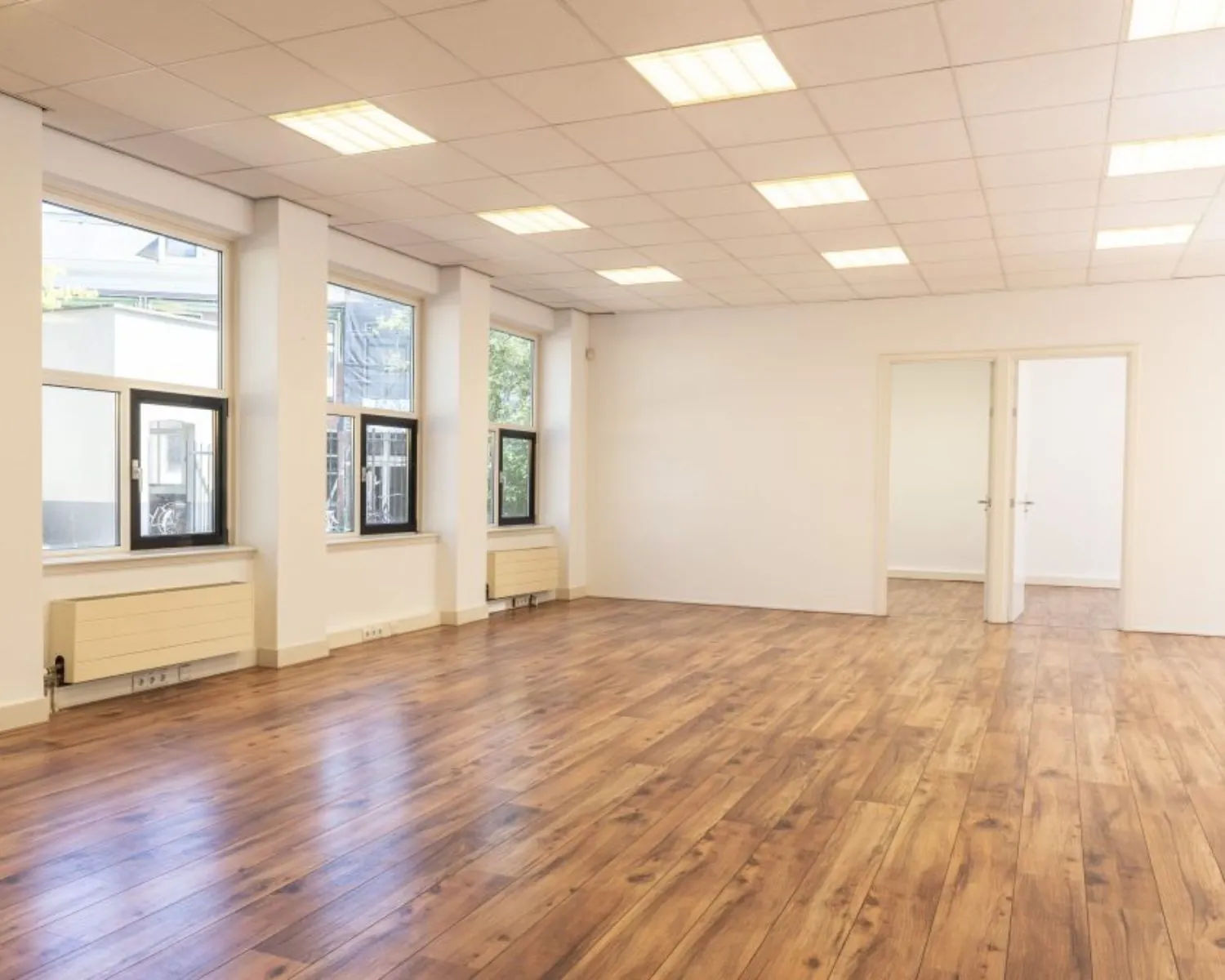 Lichte, ruime kantoorruimte met houten vloer en grote ramen aan de Wilhelminastraat 43A in Haarlem.