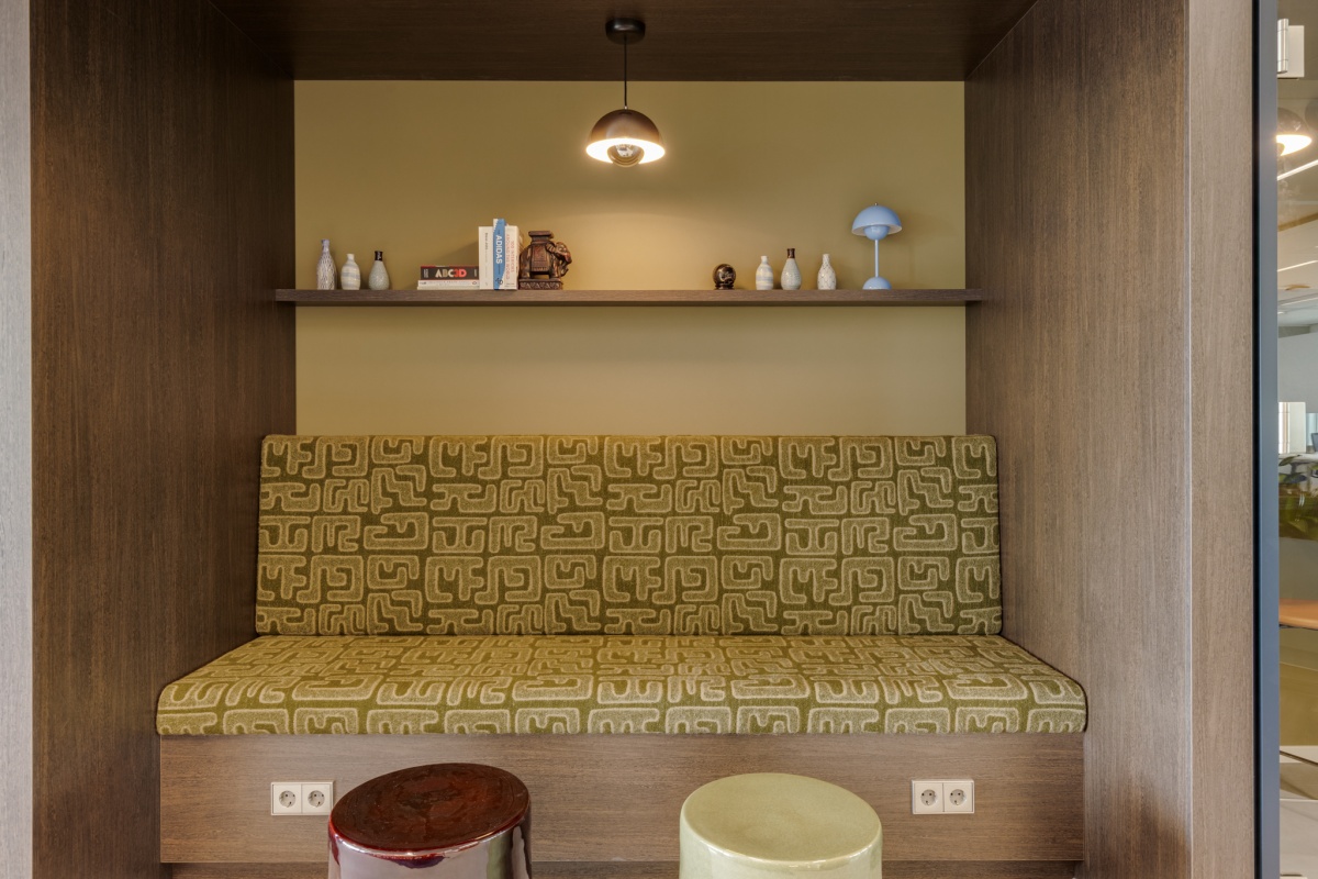 Een moderne zitplek met een groene bank en decoratieve voorwerpen op een plank erboven.