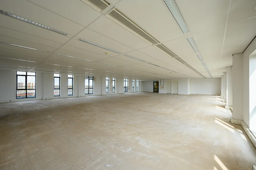Leeg kantoorpand aan de Maasstadweg met grote ramen en systeemplafond.