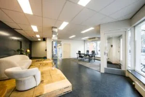 Licht en modern kantoorinterieur aan de Nassaukade met een vergadertafel, loungehoek en grote ramen aan de straatzijde.