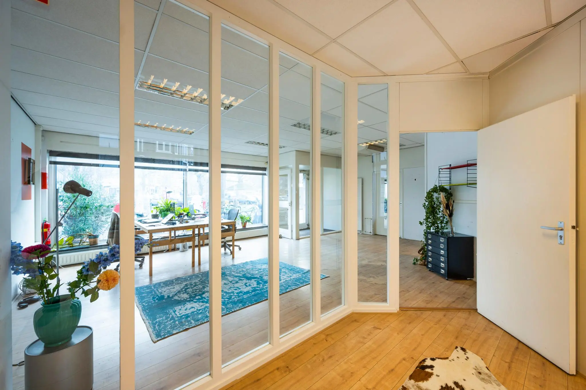 Licht en modern kantoorinterieur aan de Nassaukade met houten vloer, glazen wand en kleurrijke details.