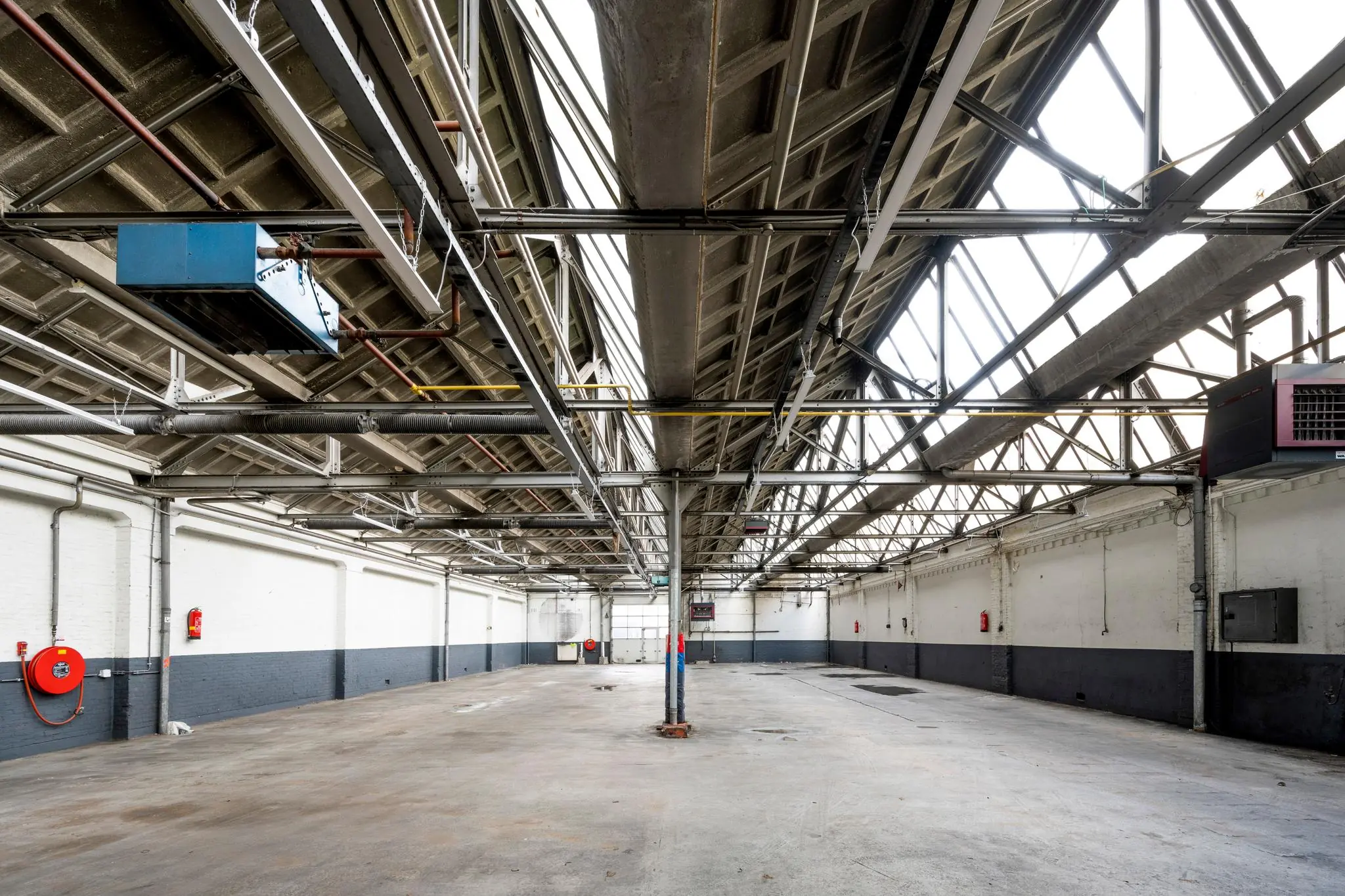 Lege industriële loods aan de Nassaukade met betonnen vloer, hoge plafonds en grote dakramen.