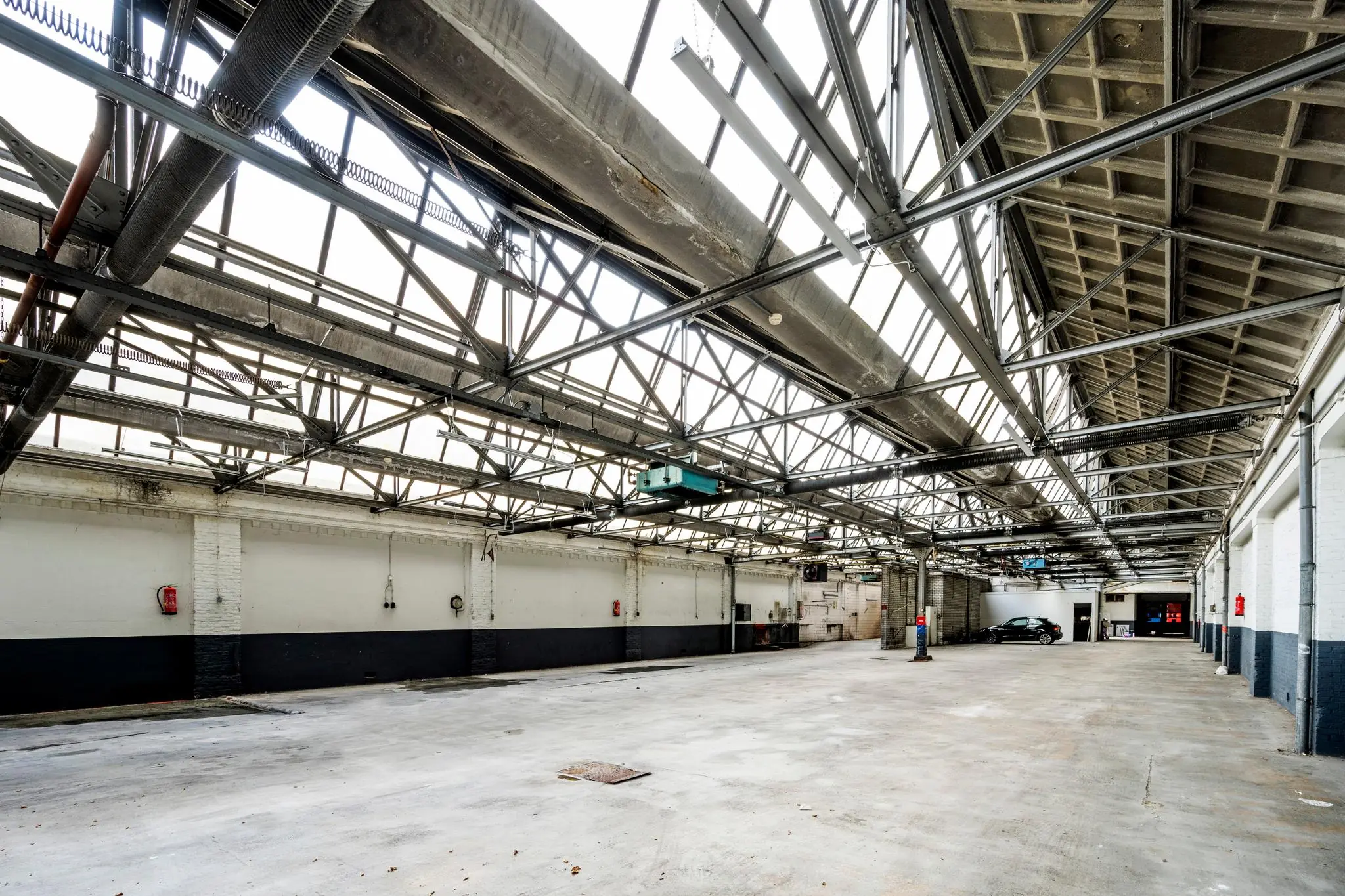 Leeg industrieel magazijn aan de Nassaukade met betonnen vloer, wit-zwarte muren en metalen dakconstructie.