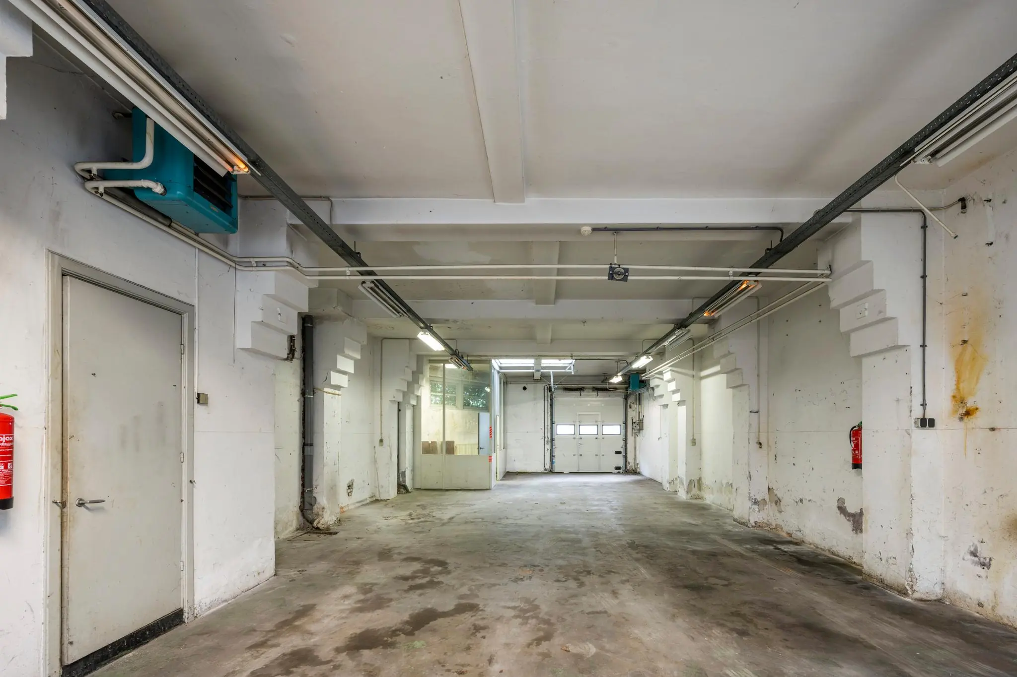 Lege, industriële garage of opslagruimte aan de Nassaukade met betonnen vloer en witte muren.