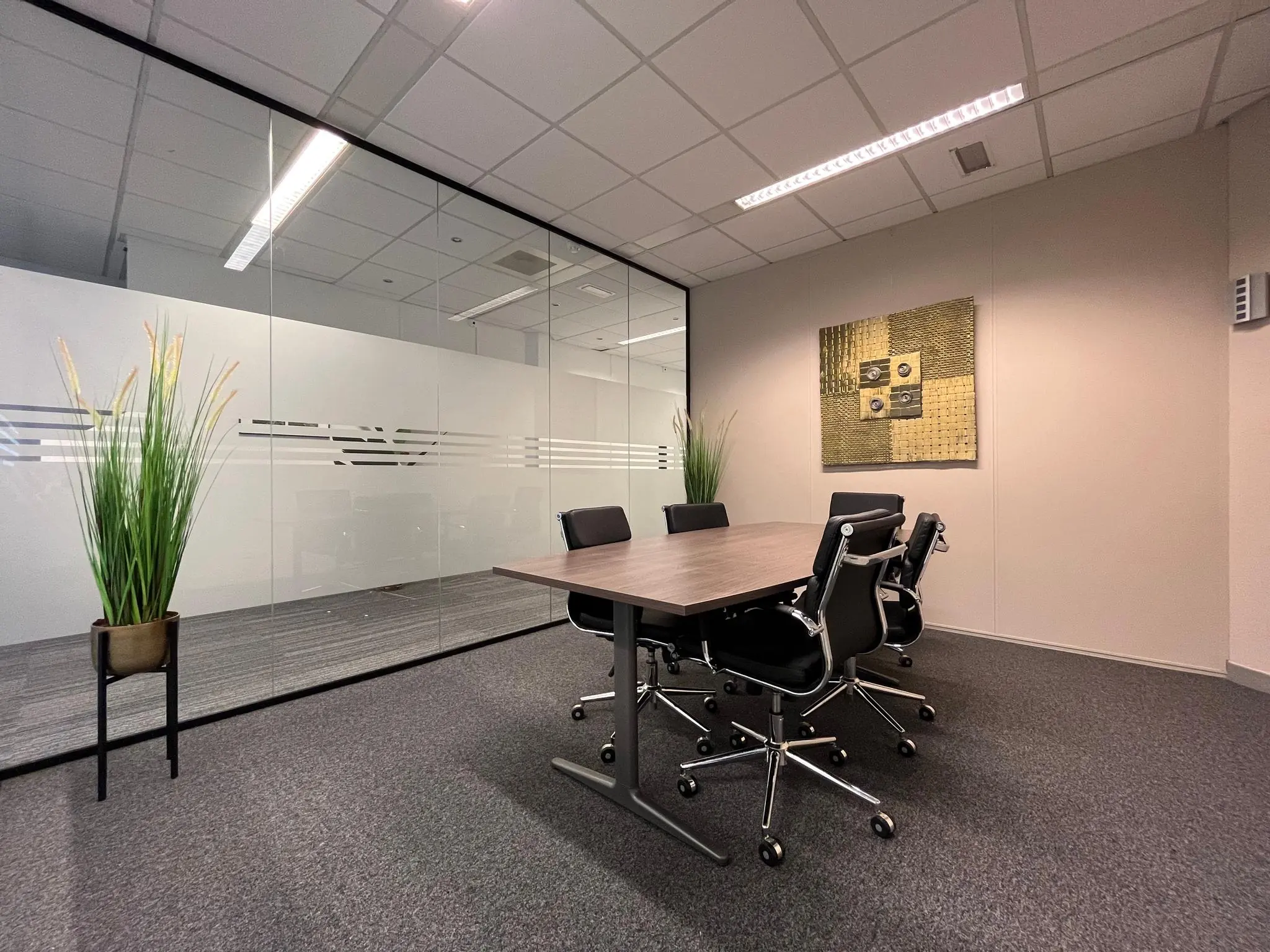 Vergaderruimte met glazen wand, moderne kantoormeubels en decoratieve wandkunst aan de Utrechtseweg.