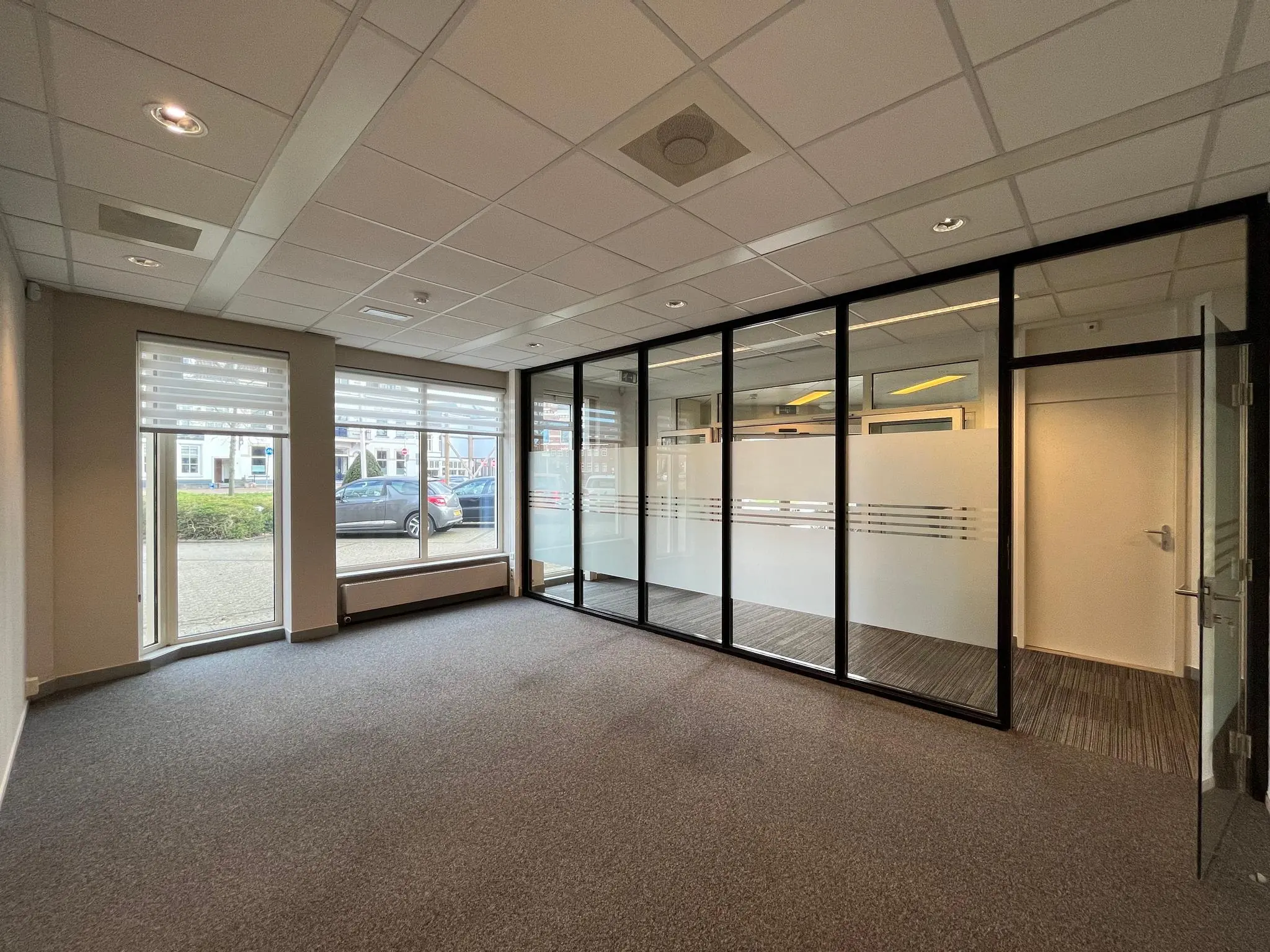 Moderne, lege kantoorruimte aan de Utrechtseweg met grote ramen en glazen scheidingswand.